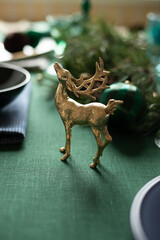 Christmas decorations festive composition with golden deer on the green linen cloth. Close up