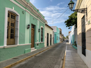 Colorful colonial street with pastel buildings and wrought iron details under clear blue sky, evoking sense of tranquility and charm