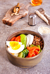 Healthy vegan nutritious bowl with buckwheat. Salad of avocado, salmon, buckwheat, egg and tomato, top view