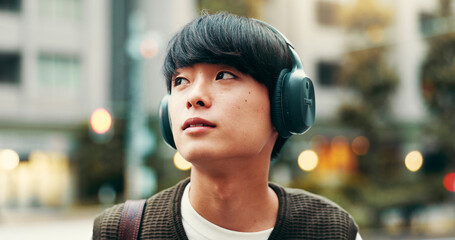 Japanese man, thinking and outdoor with podcast, headphones and vision in city street or metro. Male person, listening and music as engineering student in university for planning, tourism and commute