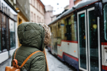 Commuter traveling by public transportation in city during winter season. Woman in hood jacket...