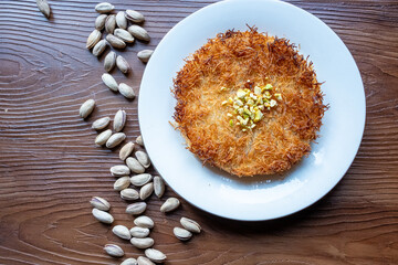 Close-up of local Turkish dessert kunefe with pistachios on a white plate