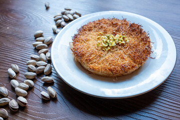 Close-up of local Turkish dessert kunefe with pistachios on a white plate
