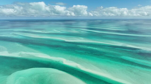 Aerial view of serene turquoise ocean with waves and sandy shoals, Schooner Cays, The Bahamas.