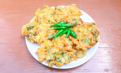 Vegetable bakwan, corn fritters are traditional Indonesian food. Flour fritters contain vegetables such as corn, cabbage, carrots, celery. Bakwan is served on a white plate