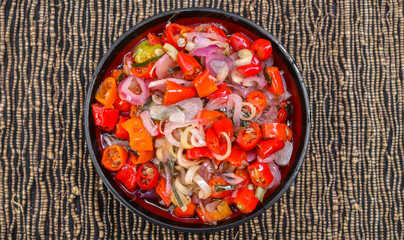 Indonesian Balinese sambal matah served in a bowl on the table decorated with kitchen spices. a type of chili sauce made from raw spices such as chilies, lemongrass, onions, lime leaves.