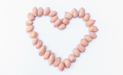 Close up Peeled peanuts isolated on white background, photo from the side. Heart shaped collection of raw nuts