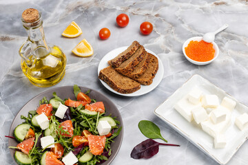 Salad with salmon, white cheese and vegetables on the plate with ingredients.