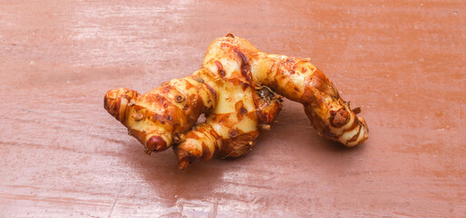 Large and fresh galangal root with slices isolated on brown background. galangal or alpinia galanga isolated. Top view.