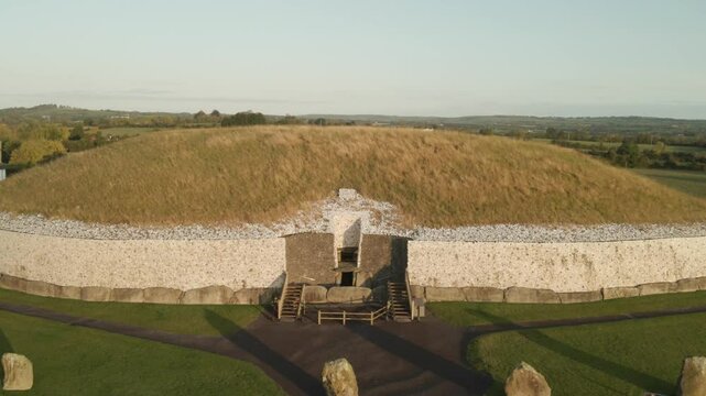 Entrance Of Newgrange Monument At Sunrise In County Meath, Ireland. - aerial pullback shot