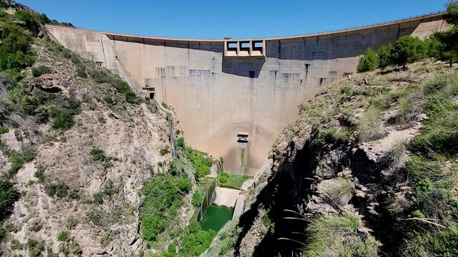 Vault dam inside a mountain canyon and river. Truck driving over the dam. Panoramic view. Beznar Dam. Spain.
