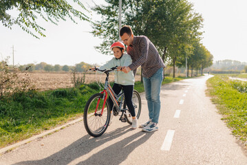 Father teaching daughter how to ride bicycle on a sunny day