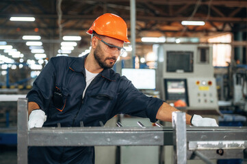 Metal pieces, standing. Man is working in the modern factory