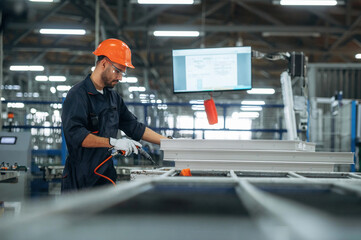 Indoors in the factory, standing. Man is working