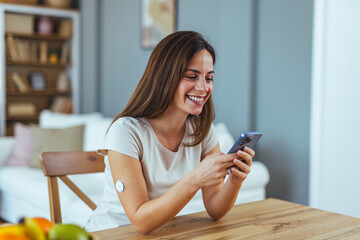 Happy Woman Checking Smartphone With Wearable Device At Home