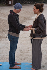 Young girl mentor practices standing on nails with her patient on the beach. Man stands on Sadhu boards. Man practices standing on nails with his mentor. Spiritual practice of standing on nails