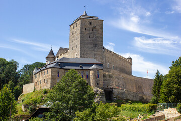 Fairytale, medieval, stone castle Kost with windows and arches. Built on a rock with green trees in...
