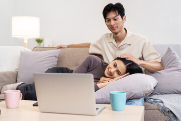 Cozy Couple Relaxing on Sofa Watching Laptop Together in Modern Living Room with Warm Lighting and Comfortable Atmosphere