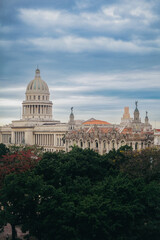 Obraz premium Historic architecture in Havana Cuba under a cloudy sky with lush greenery in the foreground