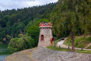 Ancient stone water tower with windows and red roof in the Czech town of Hradec Králové. Green trees in the background