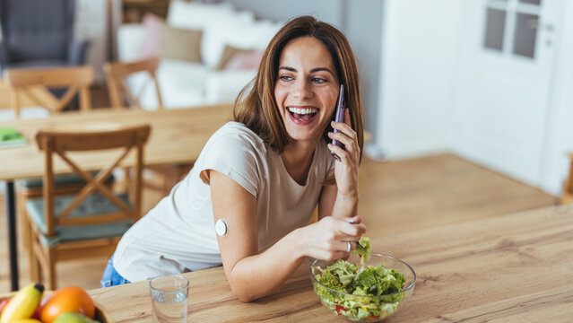 Smiling Woman Enjoying Salad While Chatting on Phone