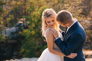 Fototapeta premium Close up portrait of a wedding couple, the groom strokes the bride on the shoulder with his hand at sunset.