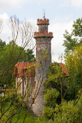 Ancient stone water tower with windows and red roof in the Czech town of Hradec Králové. Green trees in the background