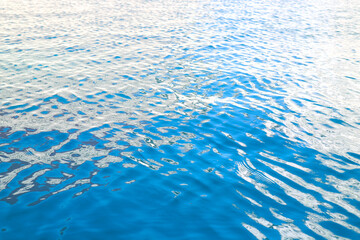 Water background, ripples and flow with waves. Blue swimming pool surface pattern exposed to sunlight. Blank space for text.