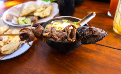 Close up and selective focus Intestine satay and liver and gizzard with chicken soto background. traditional Indonesian street food