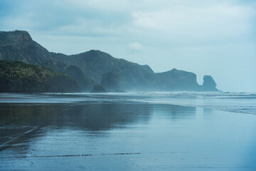 Seascape of Bethells Beach with mountain cape and wave in gloomy day at New Zealand