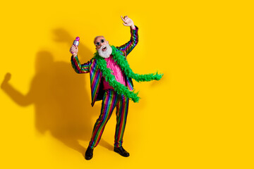 Full size photo of excited old man showman enjoy karaoke party wear glamour striped bright clothes boa sunglass isolated yellow background
