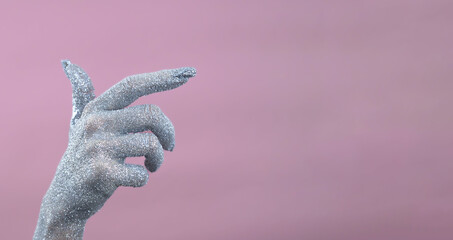 Glittering hand gesture against a soft pink background.
