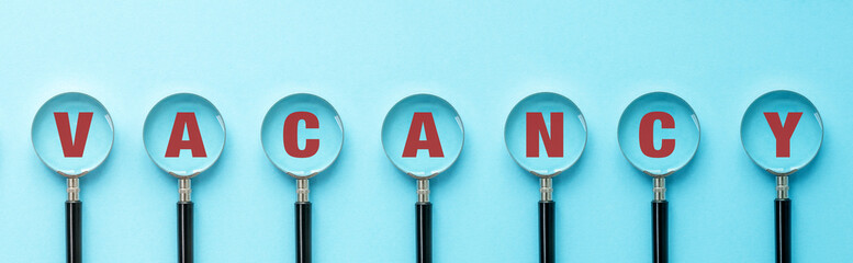 Vacancy inscription on a magnifying glass on a blue background