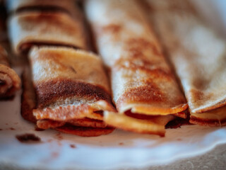 A close-up view of freshly cooked golden brown rolled pancakes, some sliced ​​to reveal the filling. The texture and crispy edges highlight their appetizing appearance.