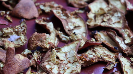 Close-up of dried pomegranate peels scattered on a red surface, highlighting texture and natural detail for eco-friendly, culinary, and sustainable themes

