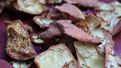 Close-up of dried pomegranate peels scattered on a red surface, highlighting texture and natural detail for eco-friendly, culinary, and sustainable themes
