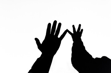 Shadow, silhouette from the hands of a child and a mother woman on a white wall, background, showing love. Photography, gesturing concept, lifestyle.