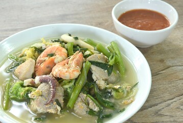 boiled sukiyaki seafood chicken and pork meat couple crispy pickled squid and shrimp with vegetable in soup on plate dipping sauce