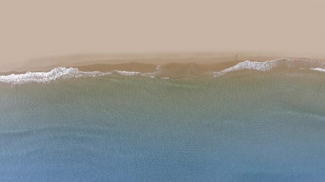 Aerial drone view of tropical beach waves reaching a sand shore peace coastline