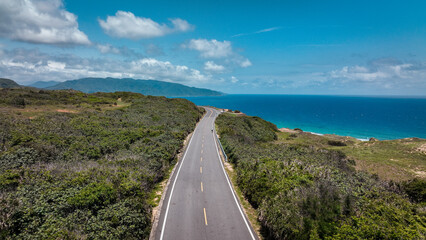 Obraz premium Scenic coastal road through lush greenery near Longpan Park in Taiwan on a sunny day