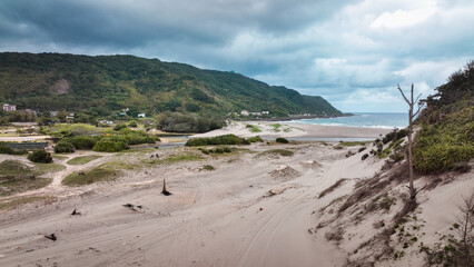 Beautiful coastal landscape of Taiwan with sandy beaches and mountains under a cloudy sky