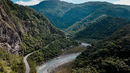 Aerial view of lush mountains and winding river in Taiwan during a sunny day in autumn