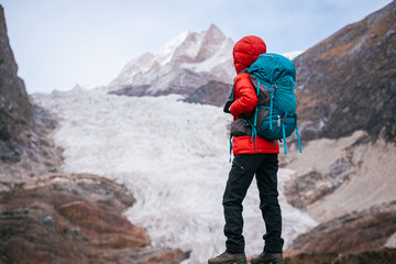 Obraz premium Backpacking woman watching the large hanging glacier on high altitude mountain top