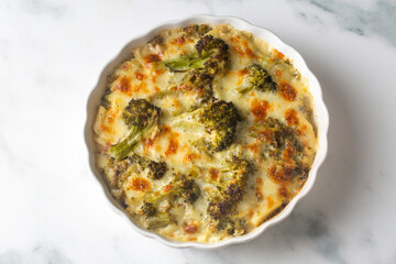 Casserole Cauliflower and broccoli baked with cheese sauce in a pot close-up on a wooden table. Horizontal top view from above. Broccoli gratin.