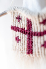 A detailed view of macramé art in the form of the Georgian flag, with a focus on the texture of the weaving and the artistic detail of the craft, emphasizing traditional methods