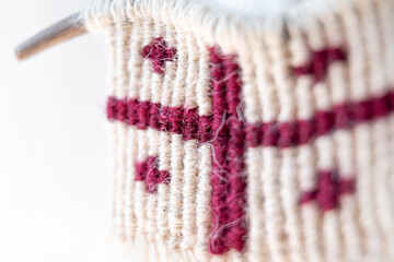 A close-up of a handmade macramé mini-panno in the design of the Georgian flag, showcasing intricate weaving and the soft texture of natural fibers, ideal for boho and rustic decor