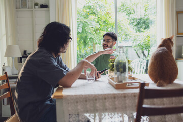 Two Men Conversing at Kitchen Table in Cozy, Sunlit Home with Cat