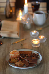 Books, lit candles, red wine, snacks and various deocration on the table. Dark academia or Halloween concept. Selective focus.