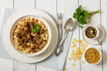 pasta rings topped with braised meat in bowl