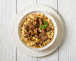 pasta rings topped with braised meat in bowl